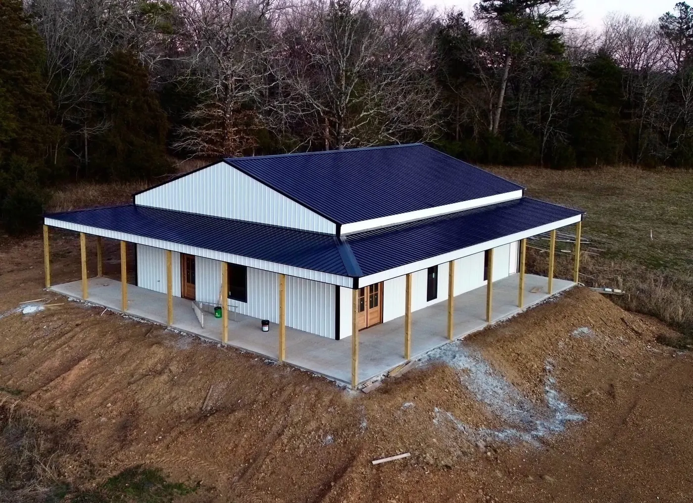 Aerial view of a metal-roof barndominium with wraparound porch