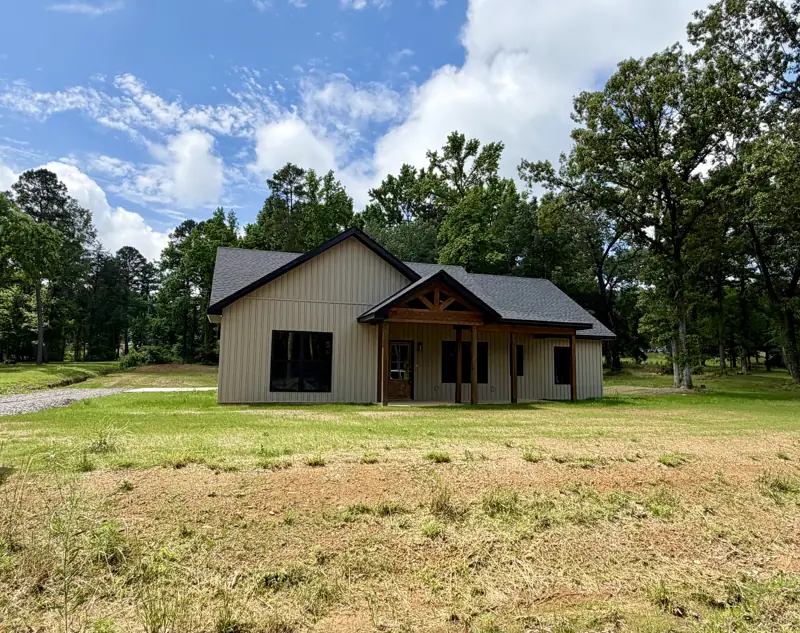 Finished tan board-and-batten custom home with a timber-frame gable porch built by C&M Innovations