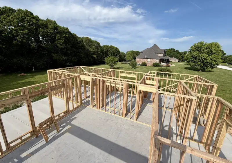 Framed walls standing on a new slab with the neighborhood behind