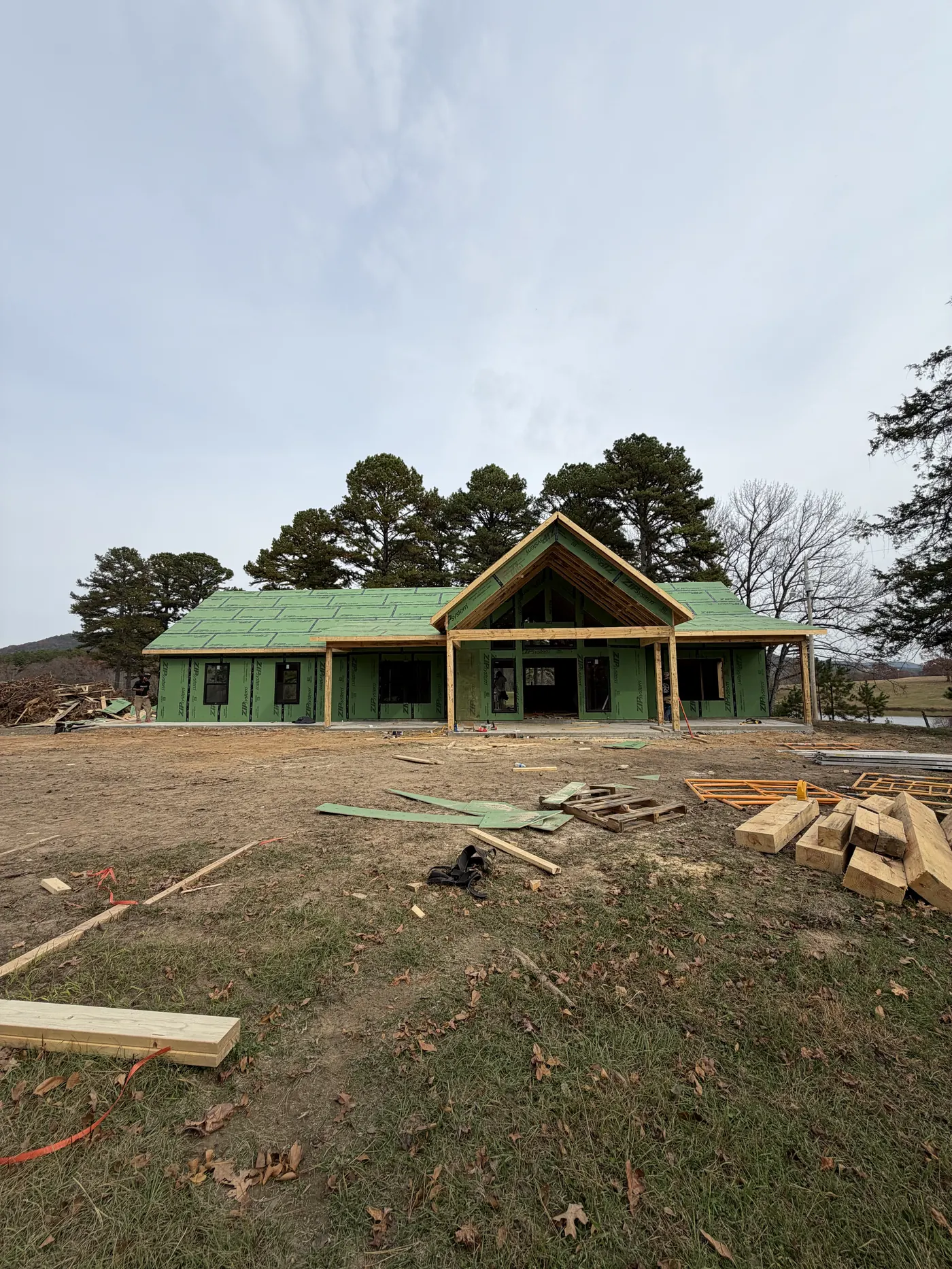 New home under construction with a steep gable porch and house wrap