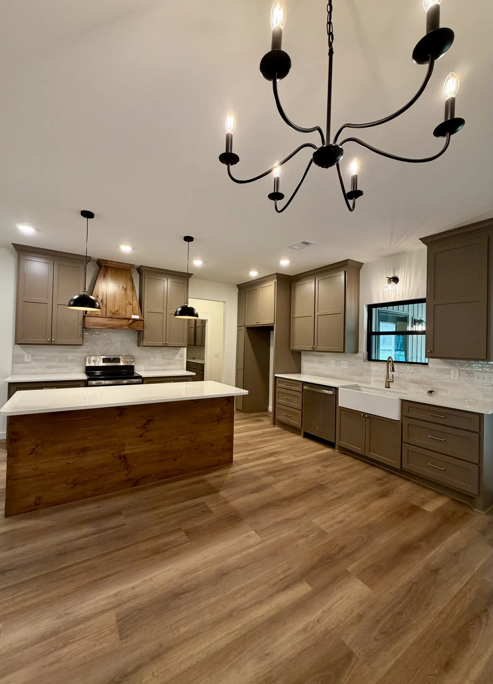 Remodeled kitchen with taupe shaker cabinets, wood-wrapped island and black chandelier