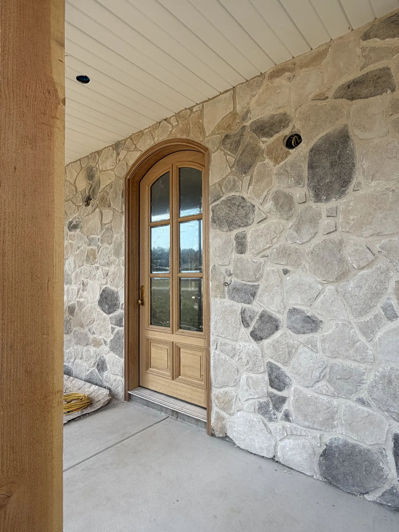 Arched wood front door set into a stone entry