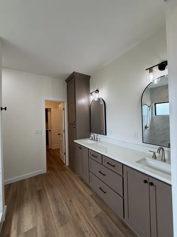 Double vanity with arched mirrors and taupe cabinets